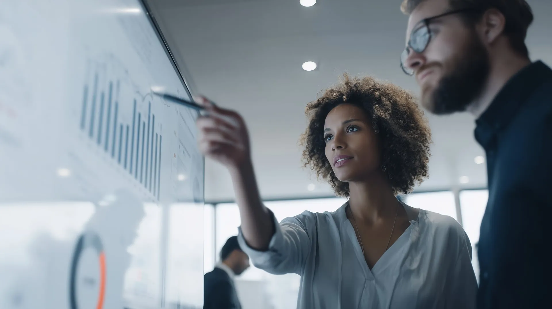 Two strategists reviewing growth charts on a large analytics display